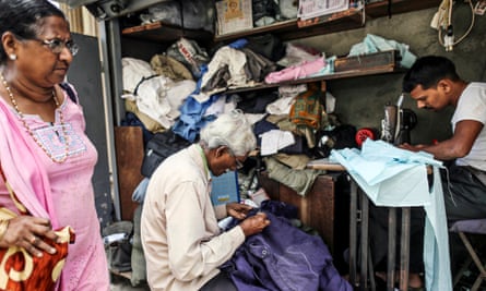 A woman walks past roadside tailors working at a stall in Mumbai, India.