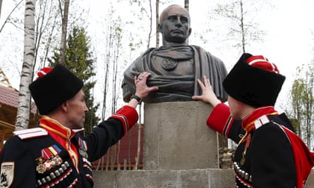 Cossacks stand next to a bust of Russian President Vladimir Putin which depicts him as a Roman emperor