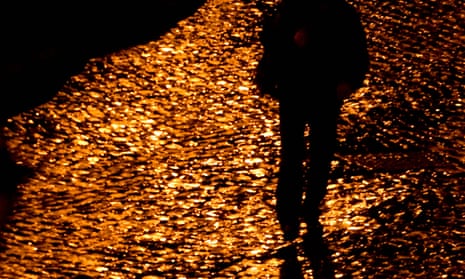 Person and their shadow against cobbled stones, illuminated by street light
