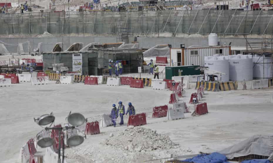Photograph taken during a government organised media tour of foreign workers walking between safety barricades at the site of the pitch of the al-Wakra stadium under construction in Doha
