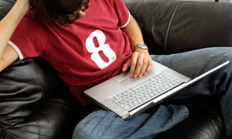 Young person using a laptop on the sofa.