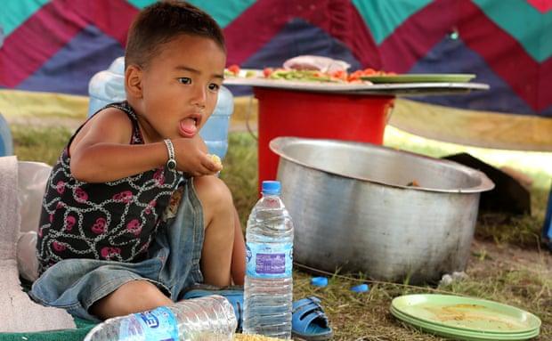 A young boy, Gigar Rama, eats lunch inside a temporary shelter in Kathmandu on Saturday.