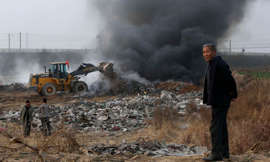 March 2014: a man looks on as a bulldozer piles up garbage to burn on the outskirts of Baoding.