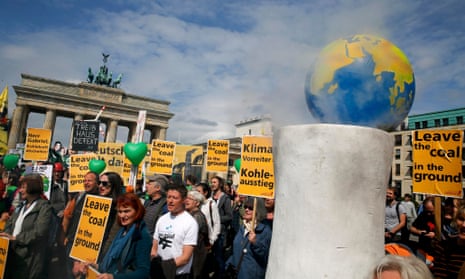Environmental activists hold banners during a rally in front of the Brandenburg Gate near the venue for the Petersberg Climate Dialogue in Berlin