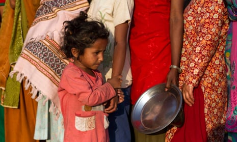 A child lines up with her mother in a temporary shelter during food distribution at Tundikhel, in Kathmandu, Nepal.