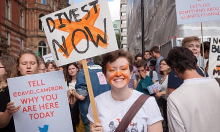 A young demonstrators smiles as he holds a placard, calling for institutions across the country to divest from fossil fuels