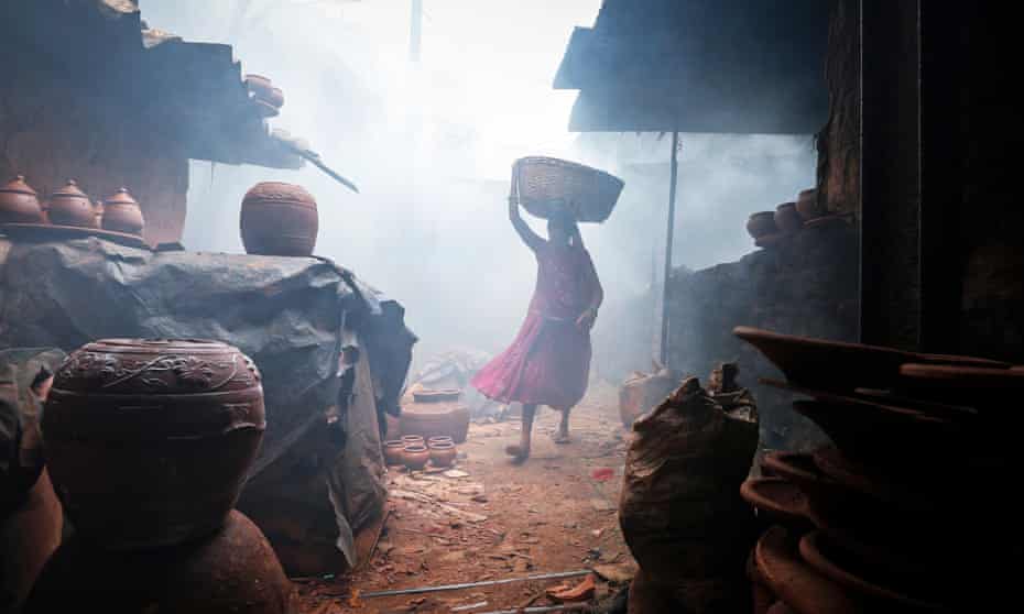 A woman potter carries earthen pots through traditional pottery kilns in the Mumbai slum of Dharavi, setting for Slumdog Millionaire.