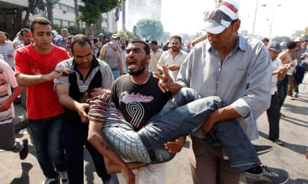 Protesters who support former Egyptian President Mohamed Mursi carry an injured man during clashes outside the Republican Guard building in Cairo July 5, 2013.
