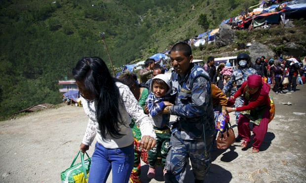 Armed Nepalese police help people in Sindhupalchok district board a helicopter to Kathmandu after last month's earthquake.