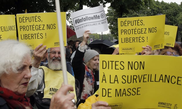 Demonstrators hold placards reading "Stop to Mass Surveillance", and "Members of Parliament Protect our Freedom", during a gathering at Invalides, Paris, to protest against the emergency government surveillance law