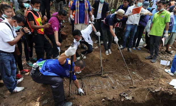 Rescue workers and forensic officials dig out skeletons from shallow graves covered by bamboo at the site of a mass grave at an abandoned jungle camp in the Sadao district of Thailand's southern Songkhla province bordering Malaysia on May 2, 2015. The badly decayed remains of at least three more migrants thought to be from Myanmar or Bangladesh were exhumed on May 2 from a mass grave in southern Thailand, as details emerged of the maltreatment endured at the remote people smugglers' camp.