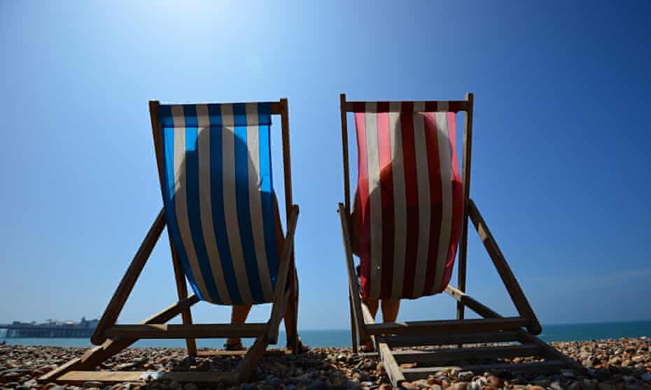 Two people sitting in deckchairs on the beach