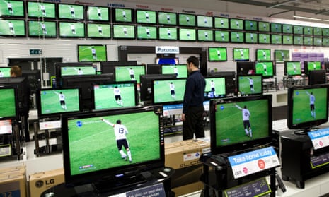 An employee checks the pricing on televisions whilst the football World Cup is shown at a Currys store in London