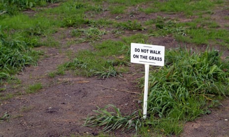 A worn lawn with a sign saying "do not walk on the grass"