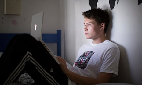 A teenage boy looking at a laptop