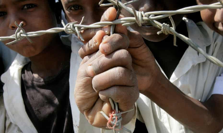 Eritrean children look on, holding the barbed wires at Sudan's Shagarab refugee camp in Kassala. The camp receives about 2,000 asylum-seekers every month, largely from Eritrea where many have fled military service.