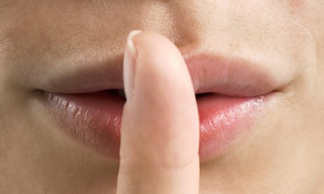A woman holds her finger to her lips