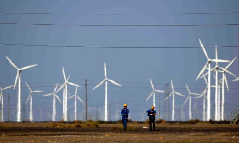 Workers walk near wind turbines for generating electricity, at a wind farm in Guazhou, 950km (590 miles) northwest of Lanzhou in China.