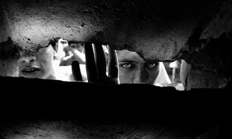 Prisoners stare through a hole in a wall at Los Teques jail, Caracas, Venezuela.