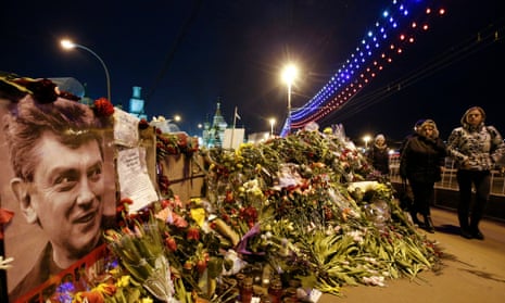 People walk past flowers at the site where Russian politician Boris Nemtsov was killed, with St. Basil’s Cathedral seen in the background, 9 March 2015.