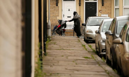A woman pushes her pram along a street in east Bradford