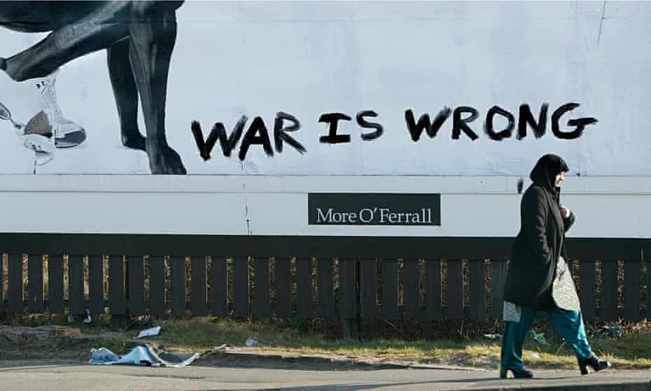A Muslim woman walks by an advertising hoarding defaced with graffiti.