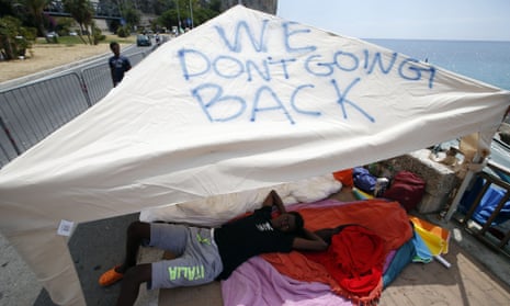 A migrant lies under a tent with the words 'We don't going back' written on it, Ventimiglia at the Italian-French border, where a group of migrants has been camping since being refused entry into France.