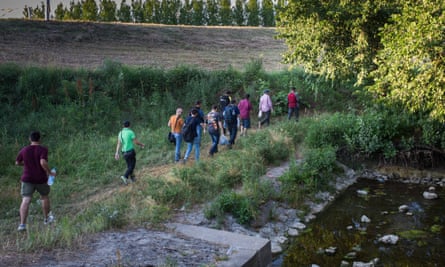 A group of Syrian migrants make their way through the woods hugging a river outside of Kanjiza, Serbia.