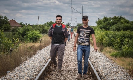 A group of Afghan migrants walk along the train tracks.