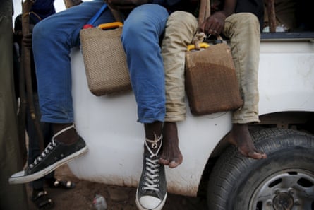 Migrants hold containers of water wrapped with wet sacks as they sit in the back of a truck in Agadez.