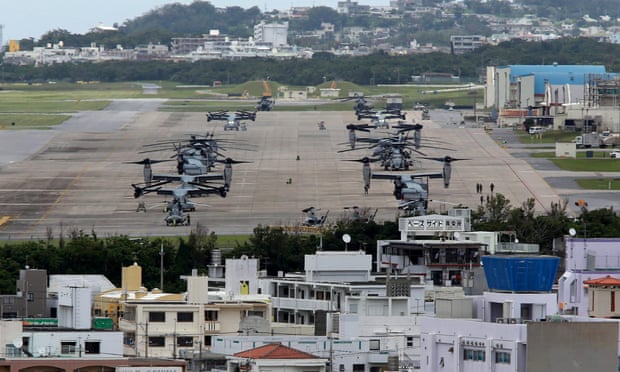 US Marine Corps MV-22 Osprey aircraft sitting on the tarmac surrounded by overcrowded residential areas in Ginowan, Okinawa.