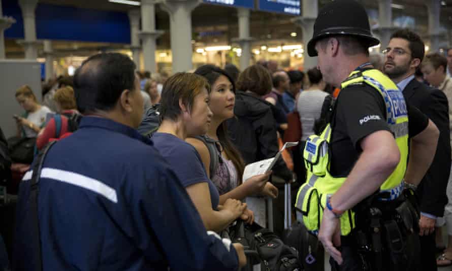 Passengers waiting at St Pancras station in London ask a police officer what to do after Eurostar trains are cancelled