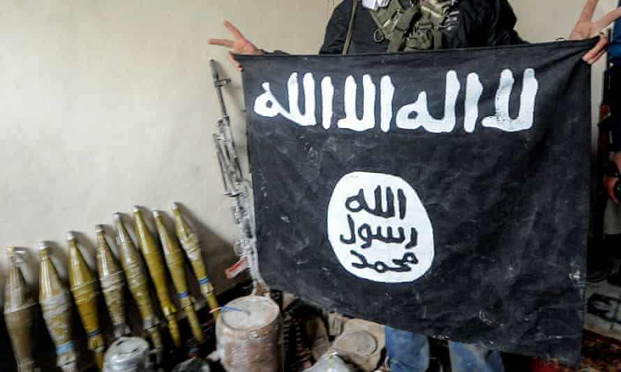 A Kurdish fighter in Kobane, Syria, holds up an Isis flag