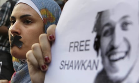 An Egyptian journalist wearing headscarf and someone holding a "free Shawkan" poster at a protest calling for his release