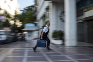 A security worker brings money to a National Bank branch in Athens