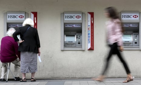 People withdraw money at a HSBC bank cash point in Paris.