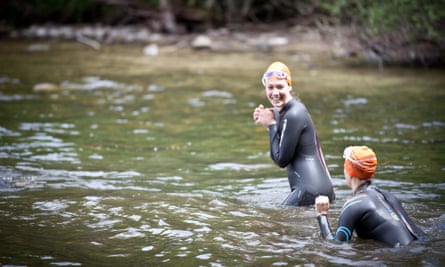 Two women in wetsuits swimming in open water.