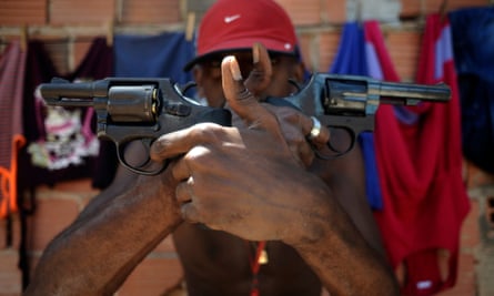 A Brazilian drug gang member nicknamed poses with a gun atop a hill overlooking a slum in Salvador.