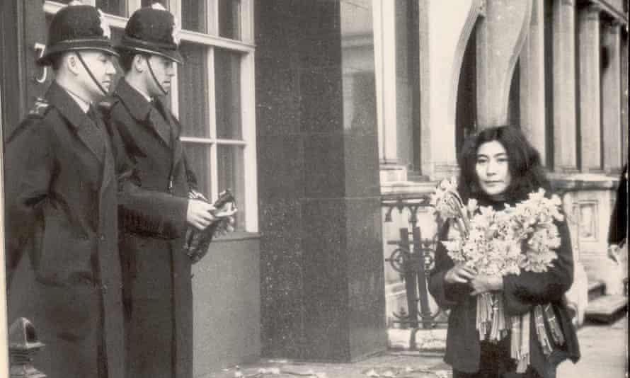Yoko Ono walking past policemen while carrying daffodils in 1966, after her film ‘No. 4 (Bottoms)’  was banned