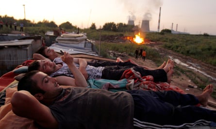Migrants workers from Tajikistan relax on the roof of their shelter after working at local market outside Moscow.