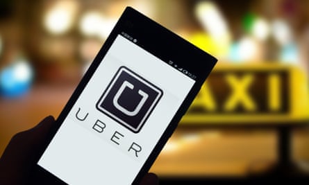 A mobile phone user looks at a logo of taxi-hailing app Uber on his smartphone .