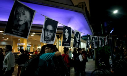 Women embrace under pictures of victims of gender violence during the Buenos demonstration.