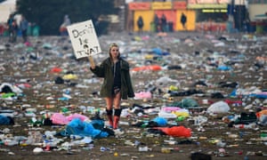 A festival-goer walks through rubbish left in front of the Pyramid stage as they leave Worthy Farm.