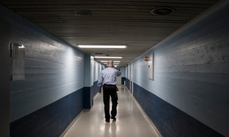 Rear view of a prison guard walking along corridor