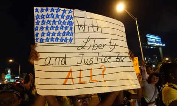 A woman holds a 'With liberty and justice for all?' sign as people blocked the I-195 freeway in Miami during Art Basel to protest the killings of Mike Brown, Eric Garner, and Israel 'Reefa' Hernandez in Miami Beach.