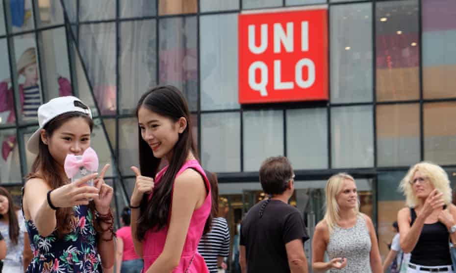 People take photos in front of a Uniqlo outlet at Sanlitun after a sex video taken in what appears to be a Uniqlo store fitting room spread online in China angering the internet watchdog.