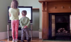brother and sister standing next to tv