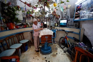 A barber cuts hair of a customer in the West Bank
