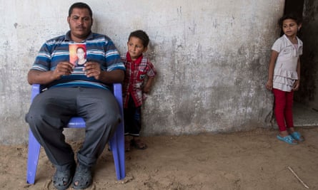Suleiman Loulahi holds up a picture of his son Bilel, aged 17, a pupil at the Doha school in Rafah who was killed in an Israeli strike on 2 August last year.
