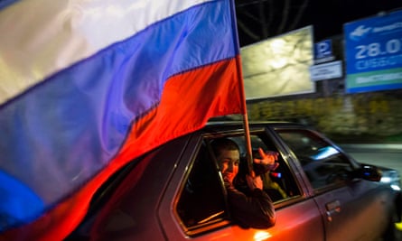 A man holding a Russian flag looks out of the car window during the celebrations for the first anniversary of the Crimean treaty-signing.